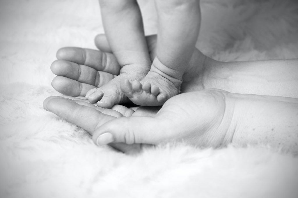 Tiny baby feet in parent's palm of hand